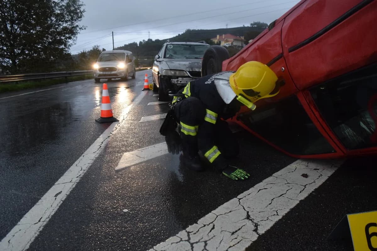 Firefighter aiding at overturned car accident on rainy road