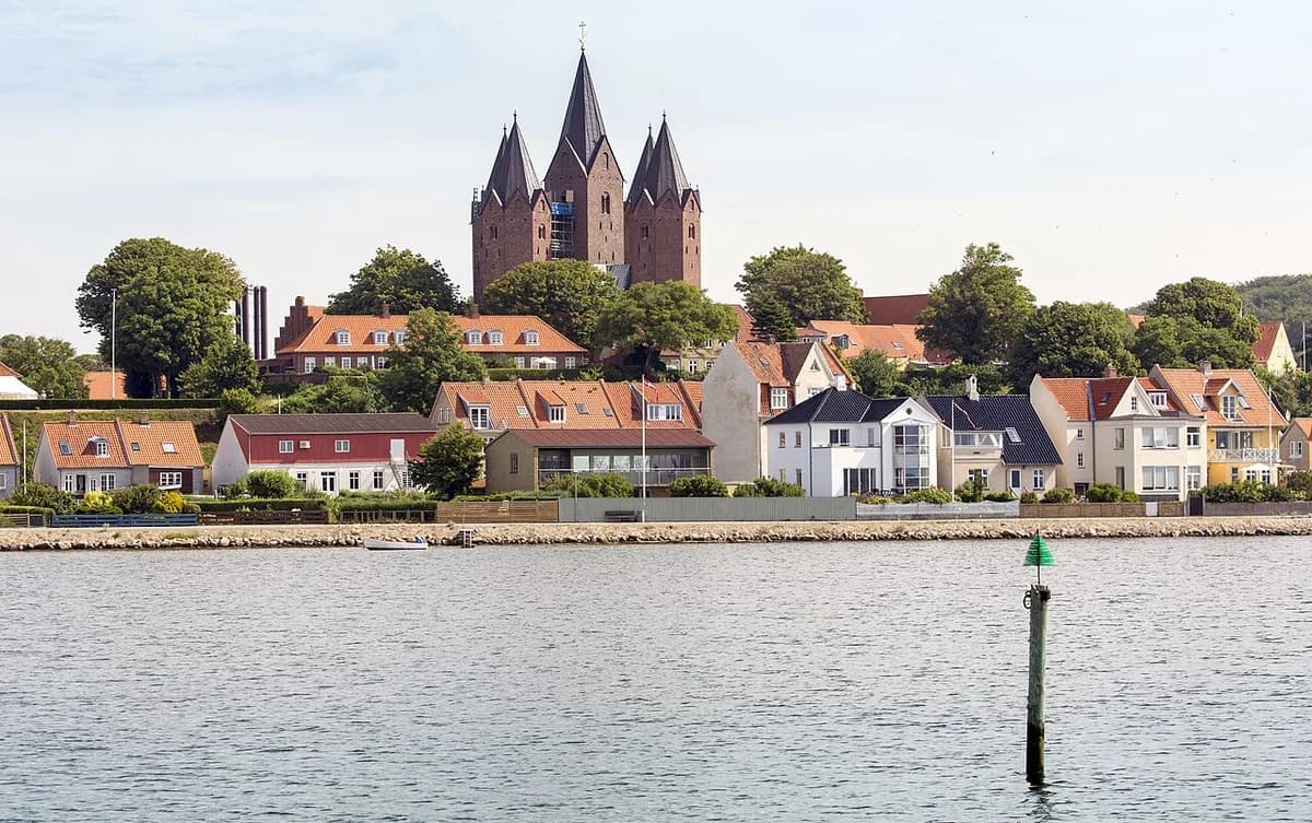 Waterfront view of Kalundborg with houses and a church on the hill.